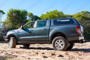 Left side view of a black PX Ford Ranger (Dual Cab) on some soft sand fitted with a 2 inch Superior Engineering nitro gas lift kit
