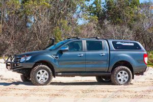 Left side view of a black PX Ford Ranger (Dual Cab) on some soft sand fitted with a 2 inch Superior Engineering nitro gas lift kit