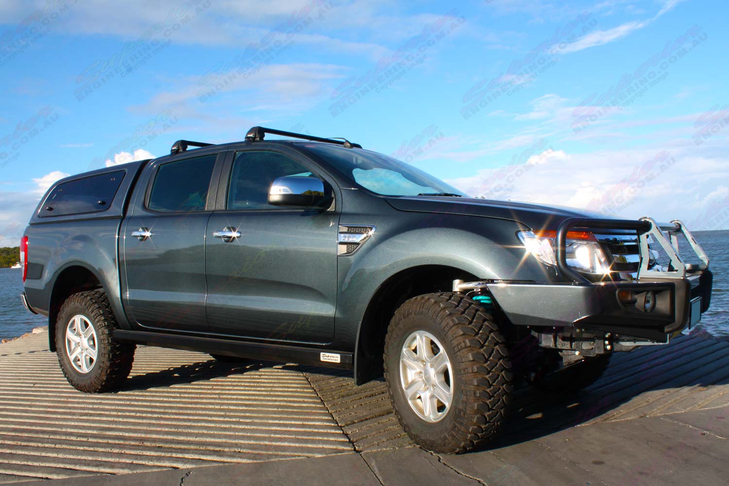 Front right view of a Dark Grey Ford Ranger dual cab fitted with superior upper control arms, rock sliders, diff guard, bash plate, recovery point and transfer case guard