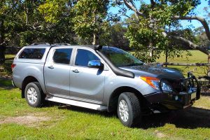 Right side view of a grey Mazda BT-50 dual cab fitted with a Black Ironman Deluxe Commercial Bullbar, Ute canopy and TJM airtec snorkel
