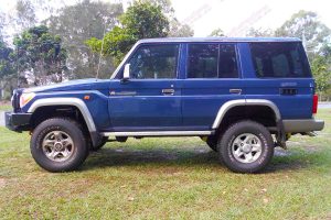 Left side view of a blue 76 Series Toyota Landcruiser wagon fitted with a Superior Remote Reservoir 2 Inch Lift Kit