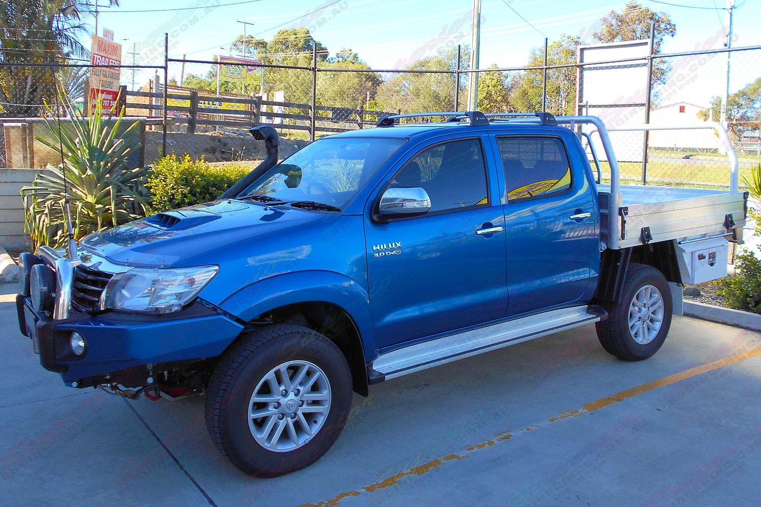 Left side view of a blue dual cab Toyota Hilux fitted with a 2 inch Bilstein lift kit, roof rack, snorkel, tool boxes, uhf radio & antenna
