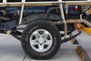 Left side closeup view of a heavy duty leaf spring pack, fixed pins and extended shackles fitted to the rear of the single cab 79 series landcruiser