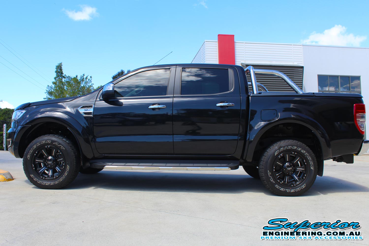 Left side view of a black PX Ford Ranger (Dual Cab) fitted with a 40mm Ironman 4x4 lift kit out the front of the Deception Bay 4WD retail store