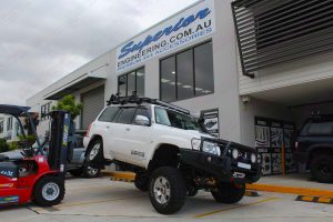 Front right view of a GU Nissan Patrol Wagon testing out the rear flex on the forklift after being fitted with a Superior Remote Reservoir Hybrid Superflex 4 Inch Lift Kit