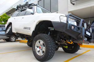 Front right view of a GU Nissan Patrol Wagon testing out the flex on the forklift after being fitted with a 4 inch Superior Remote Reservoir Hybrid Superflex Lift Kit