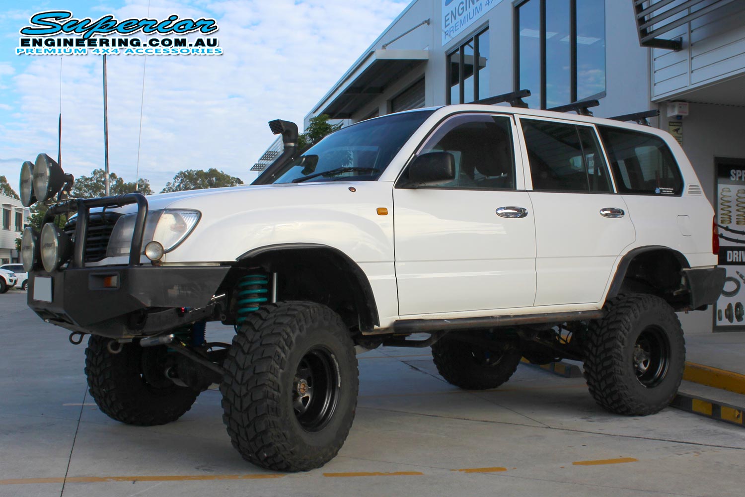 Left side view of a white 105 Series Toyota Landcruiser 4wd fitted with the huge 6 inch lift kit by Superior Engineering