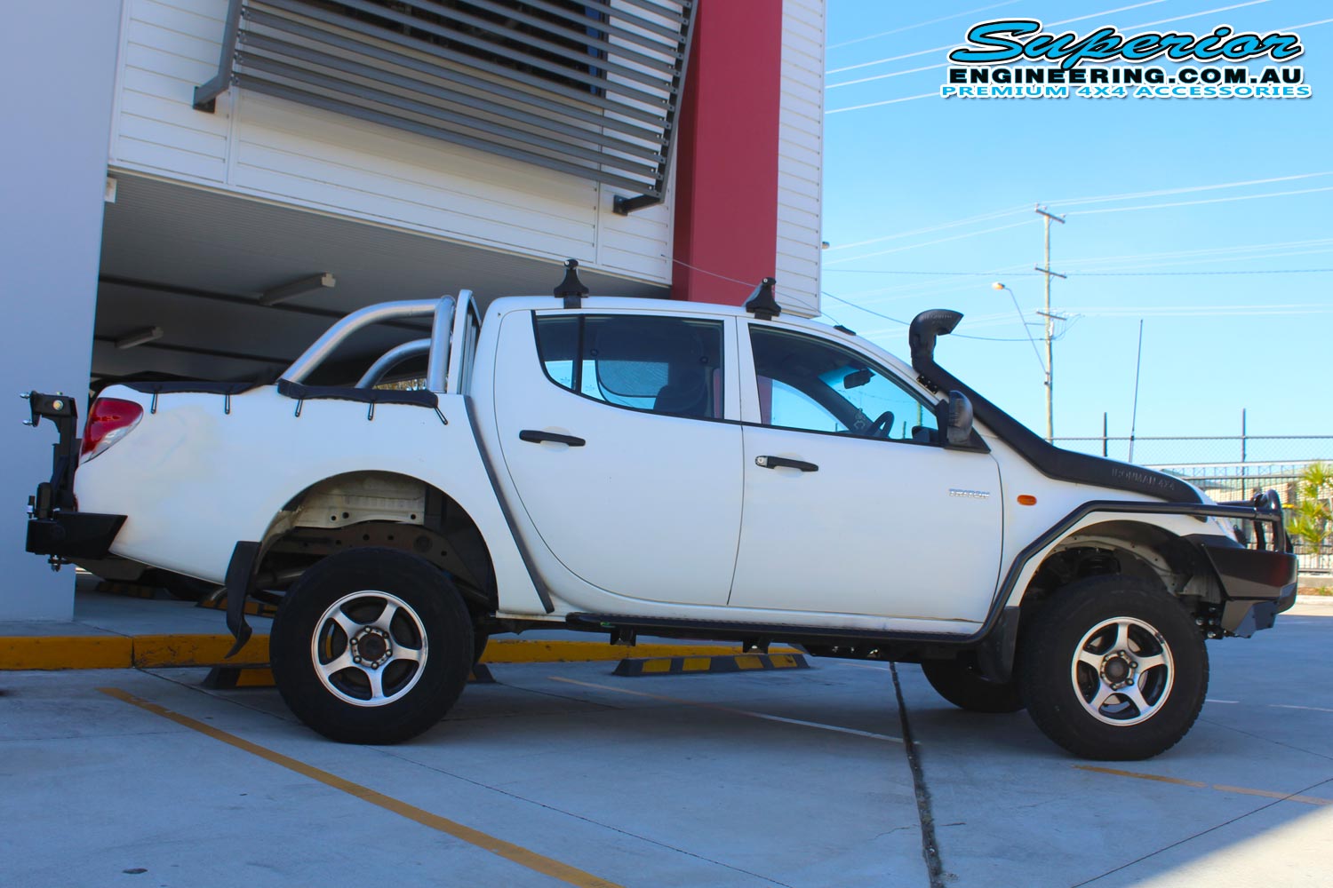 Right side view of a white Mitsubishi Triton four wheel drive after being fitted with a 20mm Bilstein lift kit and a full range of 4x4 accessories from Superior Engineering