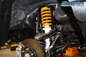 Closeup view of a single Ironman 4x4 strut and coil spring fitted to the front of the Mitsubishi Pajero Sport Wagon while on the hoist at Superior Engineering