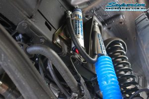 Closeup view of a single superior remote reservoir shock and coil spring fitted to the 79 Series Toyota Landcruiser while on the hoist at the Superior workshop