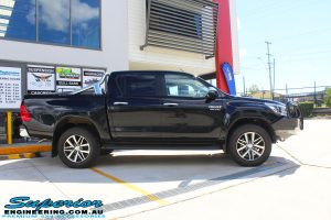 Side view of a Black Toyota Hilux Revo before fitting a 2" inch lift with Dobinsons Coil & Leaf Springs with a Superior Remote Reservoir Rear Shock & Front Strut