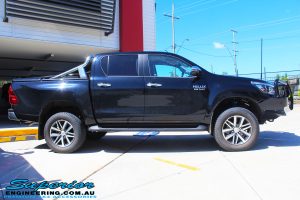 Side view of a Black Toyota Hilux Revo after fitting a 2" inch lift with Dobinsons Coil & Leaf Springs with a Superior Remote Reservoir Rear Shock & Front Strut