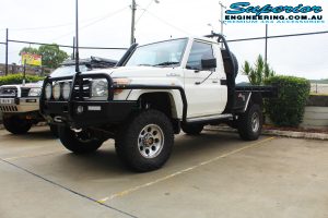 Front right view of a white single cab 79 Series Toyota Landcruiser after fitting a 4" inch Superior Remote Reservoir Superflex Kit + Tru Tracker Kit