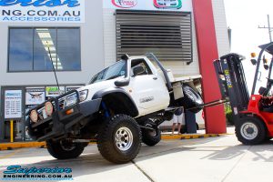 Left front side view of a White GU Patrol Ute showing its flex after fitment of a Superior Nitro Gas Hyperflex 4" Inch Lift Kit, Tie Rod Heim Joint + Coil Tower Brace Kit