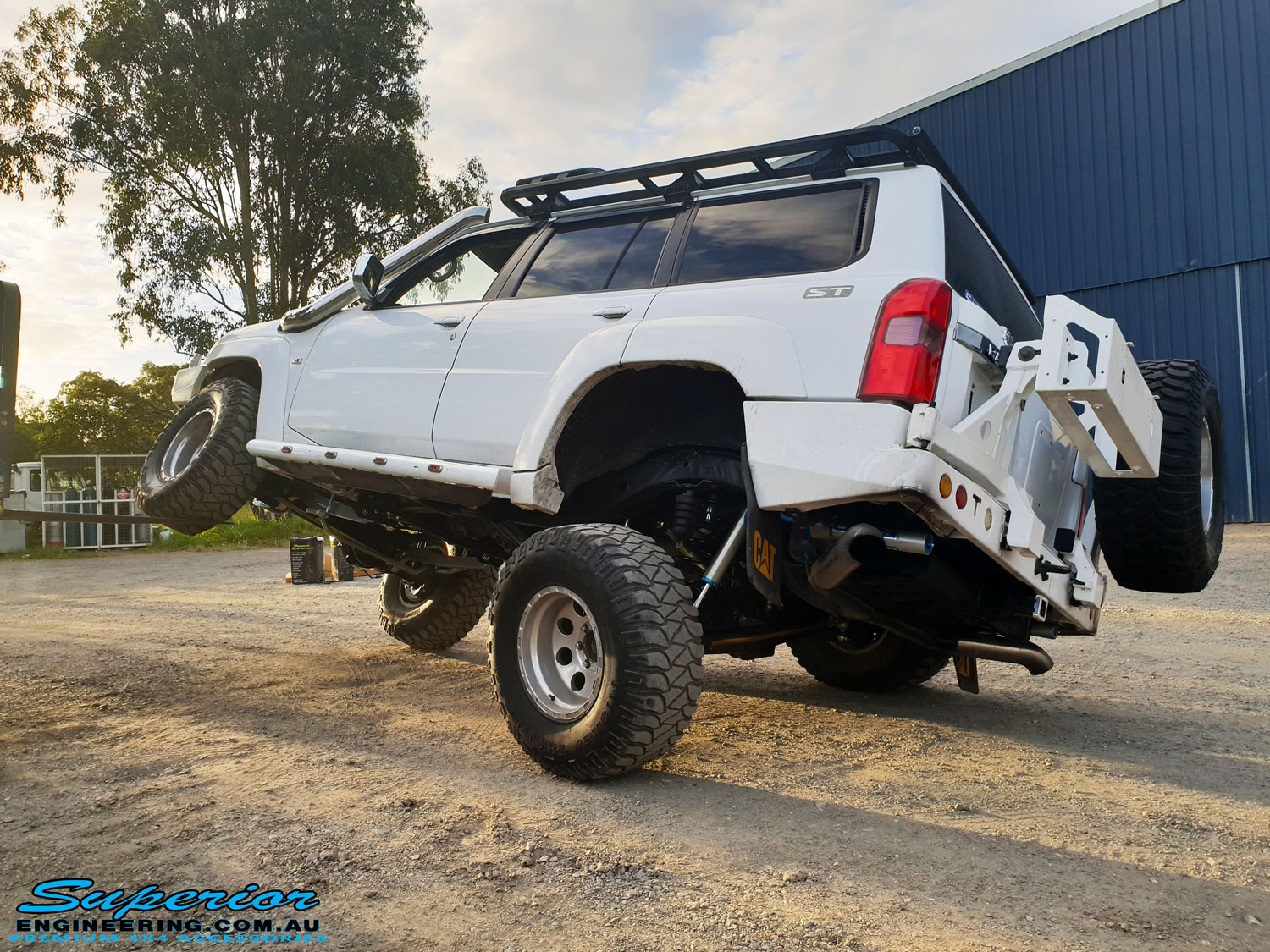 Left rear view of a White Nissan GU Patrol Wagon flexing its front left wheel after the fitment of a range of high quality Superior Engineering 4x4 Suspension & Accessories