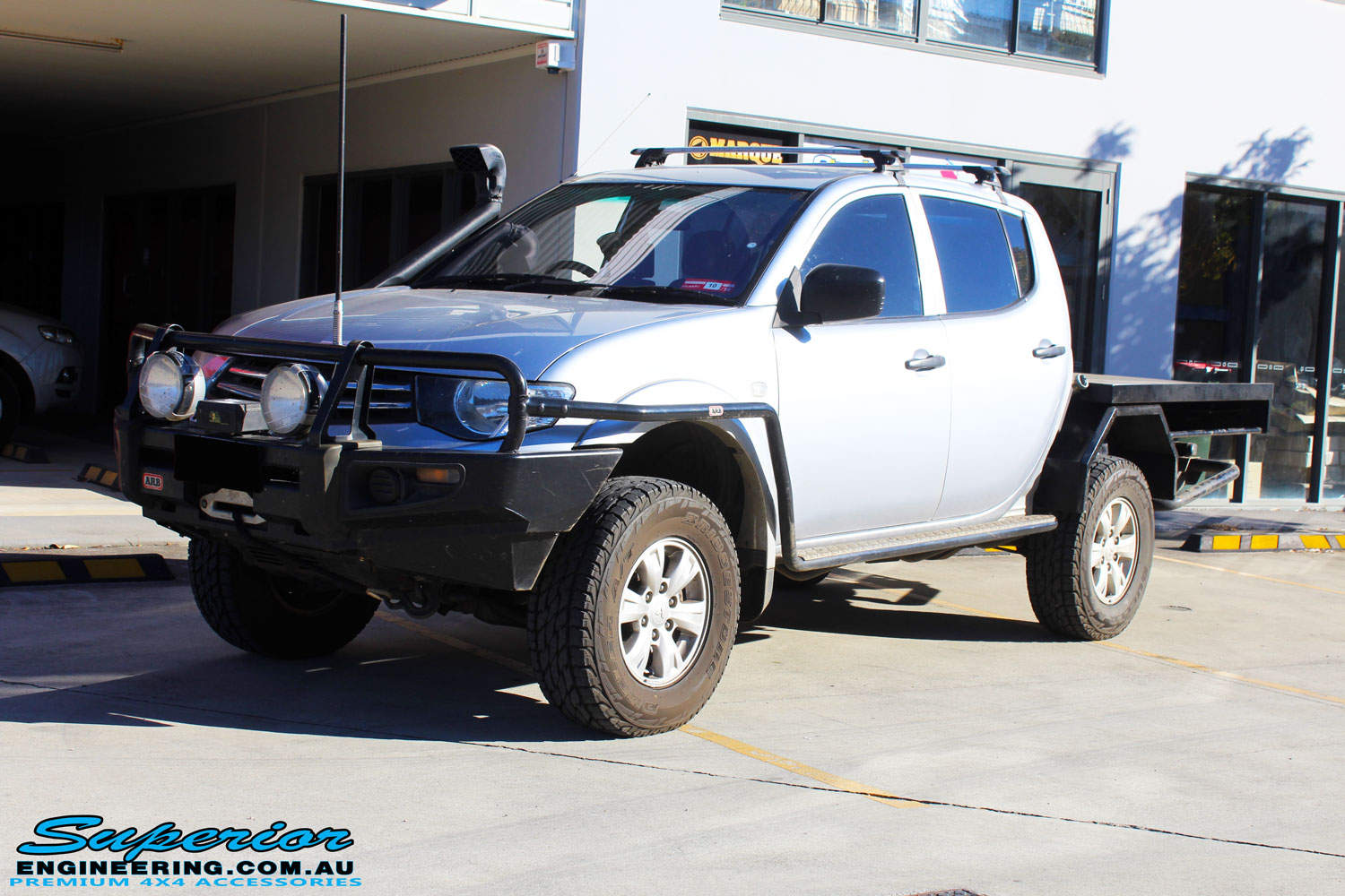 Left front side view of a Mitsubishi MN Triton in Silver On The Hoist @ Superior being fitted with a Chassis Brace/Repair Plate