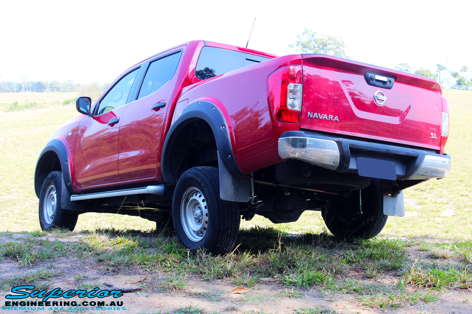 Rear left side view of the Red Nissan NP300 Navara Dual Cab flexing after fitment of a Superior Remote Reservoir 3" Inch Lift Kit