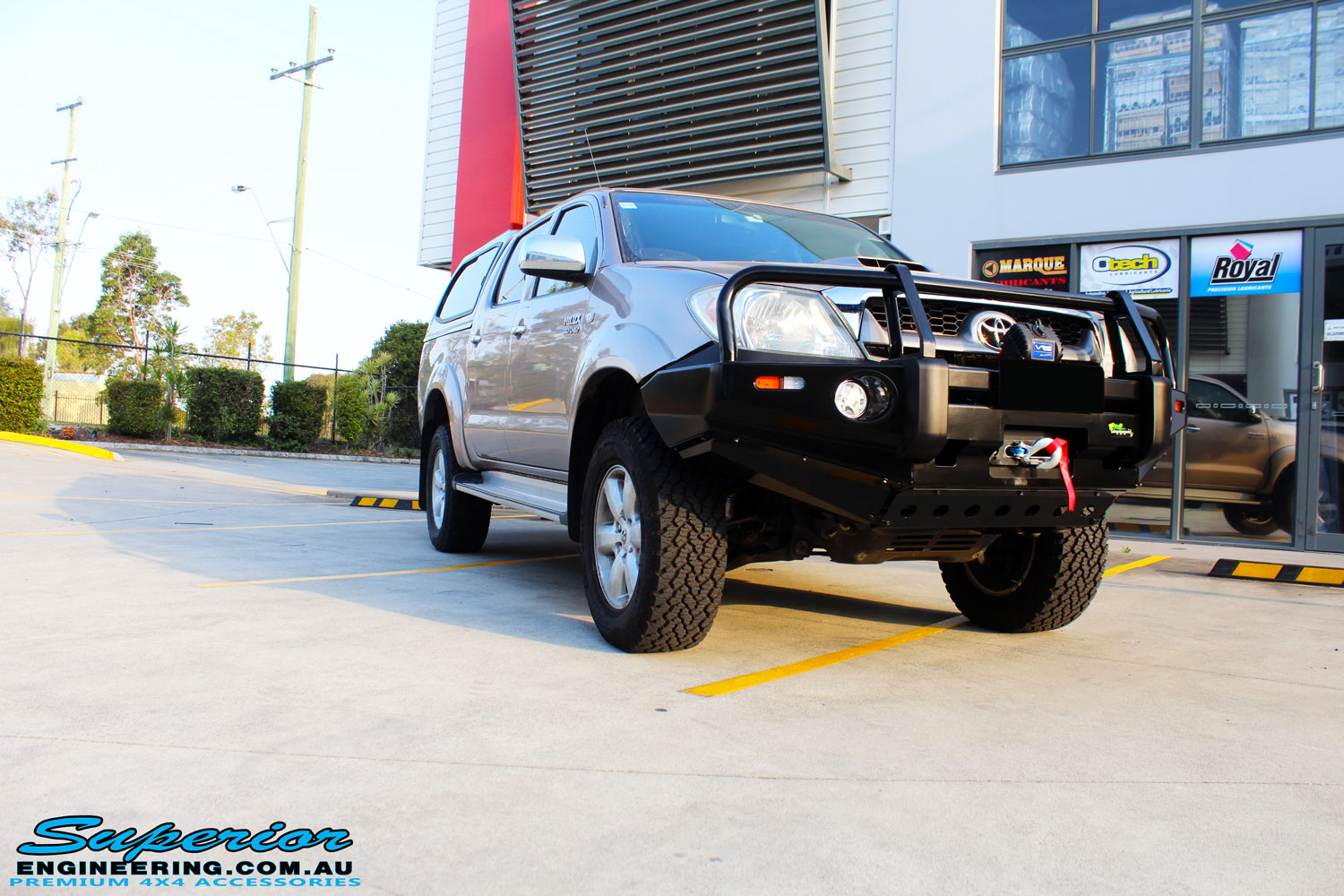 Right front side view of a Gold Toyota Vigo Hilux Dual Cab after fitment of EFS Coil Springs, Ironman 4x4 Deluxe Commercial Black Bullbar & VRS Winch