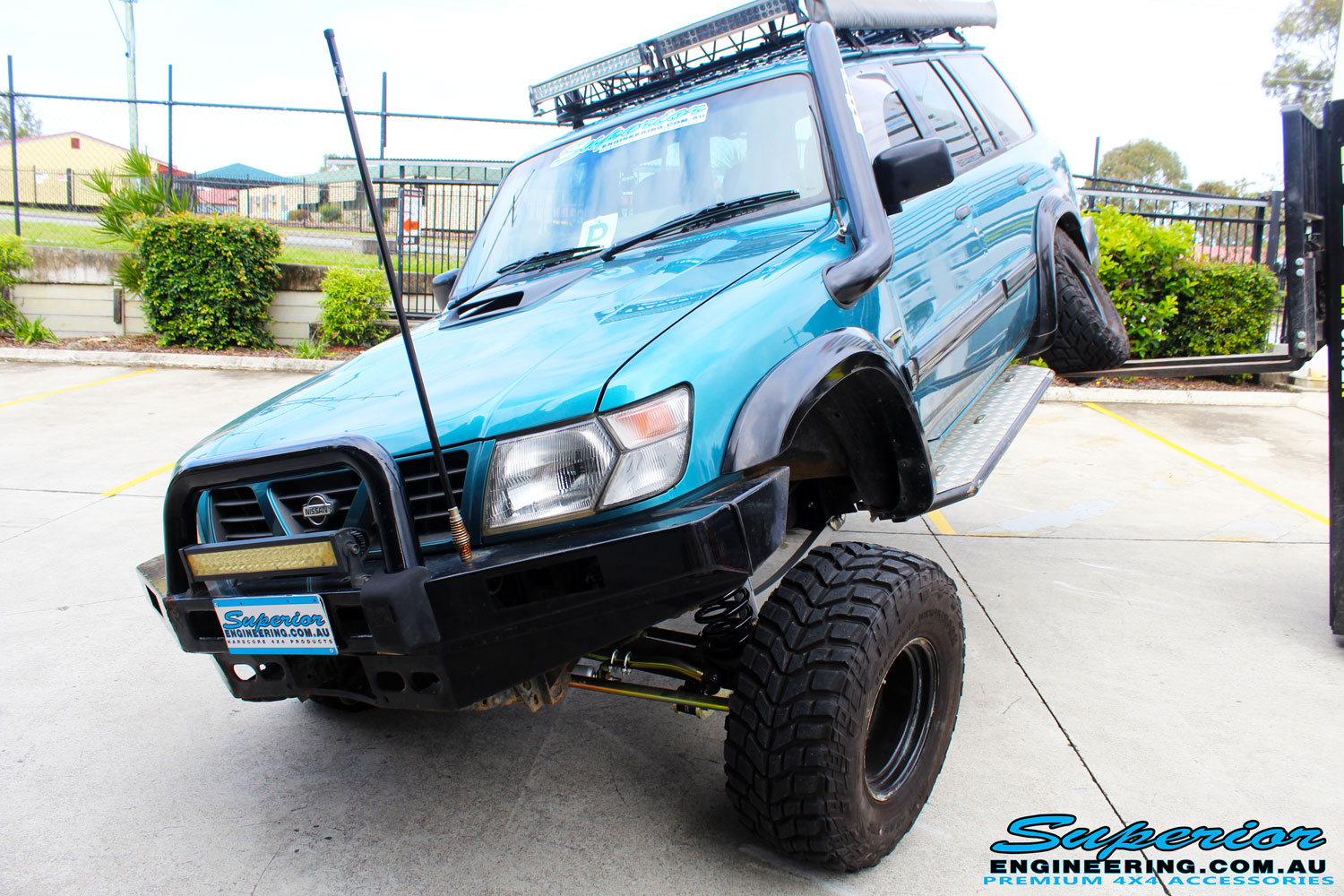Left front side view of a Blue Nissan GU Patrol flexing its left rear wheel after fitment of a Superior Nitro Gas Hyperflex 3" Inch Lift Kit with Superior Control Arms Long Arm Kit