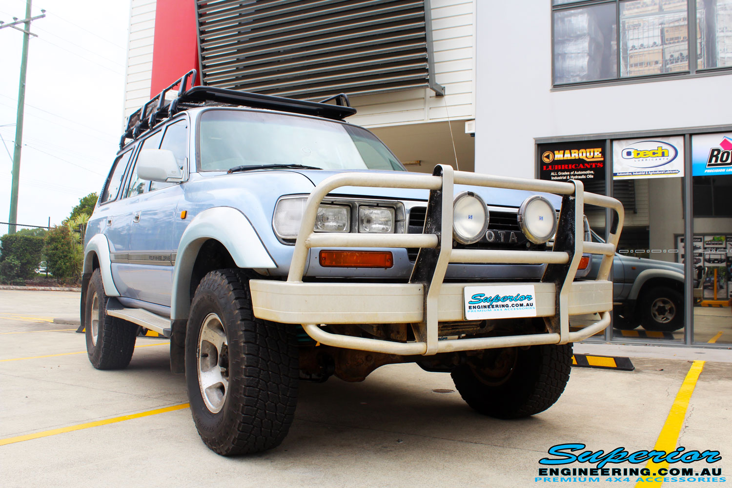 Right front side view of a Blue Marlin Toyota 80 Series Landcruiser Wagon after fitment of a Superior Nitro Gas 2" Inch Lift Kit, Superior Radius Arm Rear Bushes & Superior Swaybar Extensions